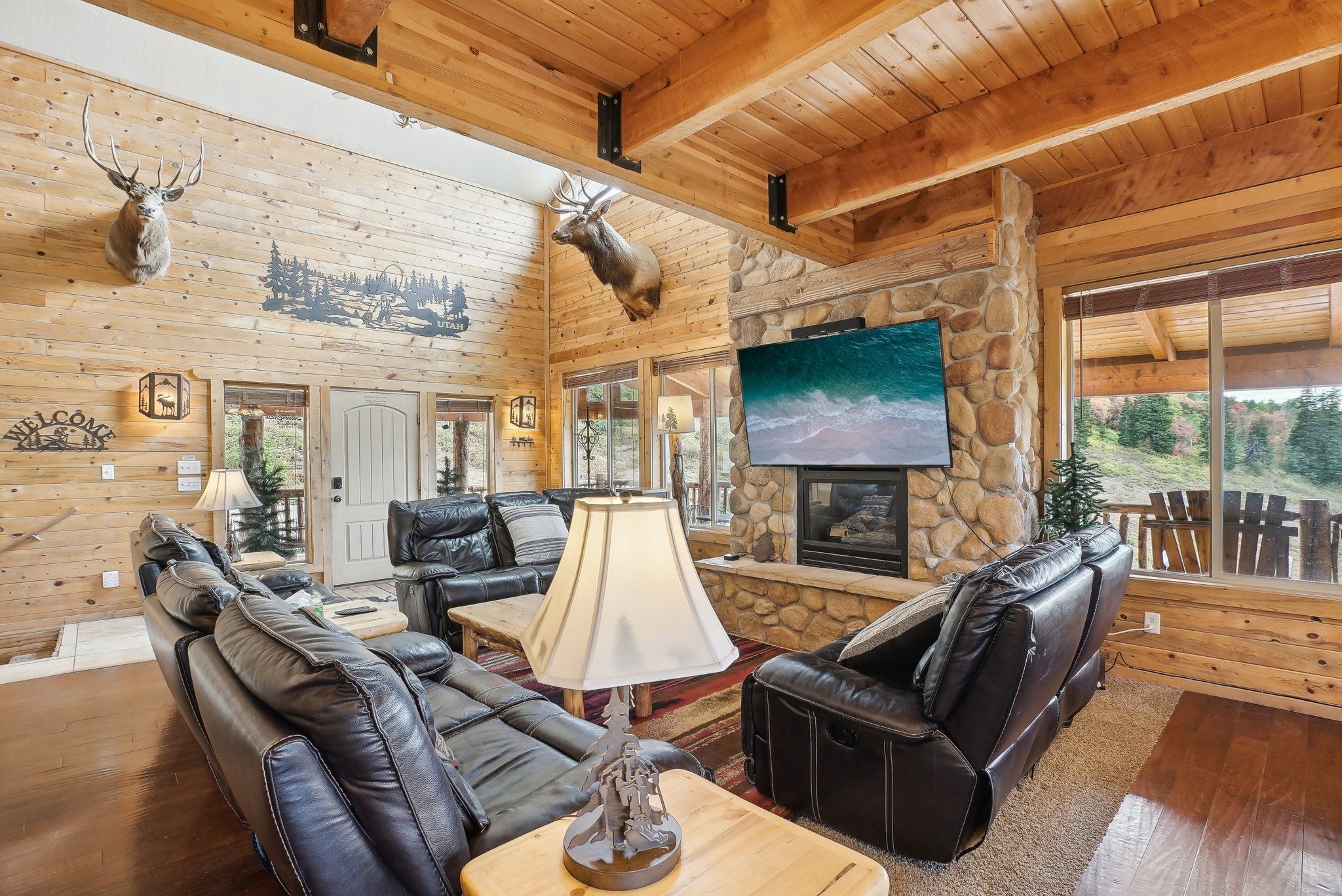 Two-story log great room with leather seating and a river-rock fireplace