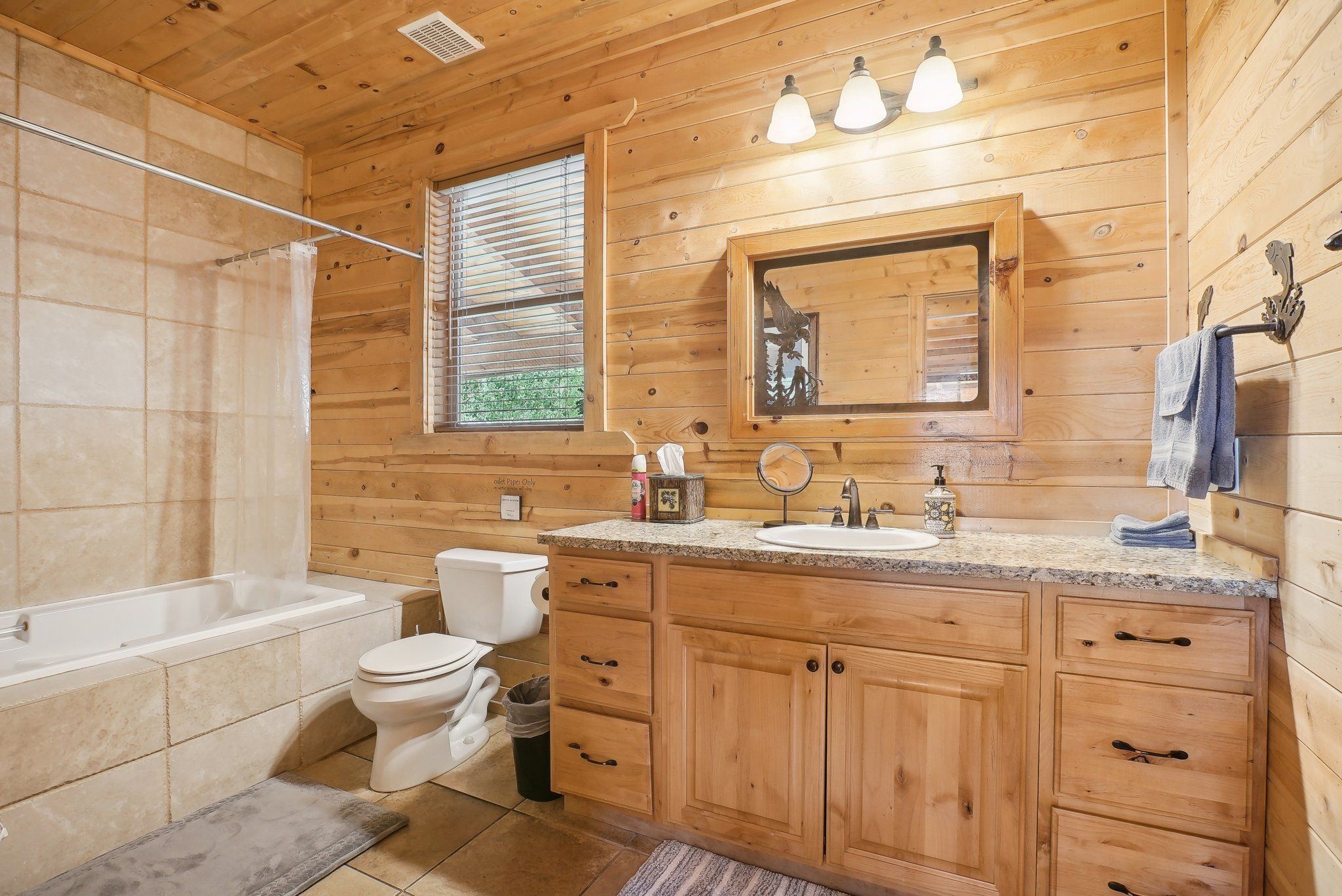 Main-floor full bathroom with wood cabinetry and tiled shower