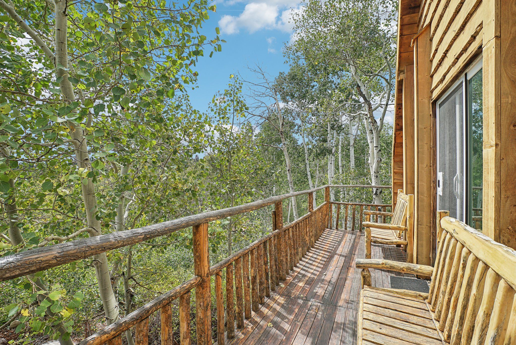 Log rocking chairs on the lodge deck beside the aspens