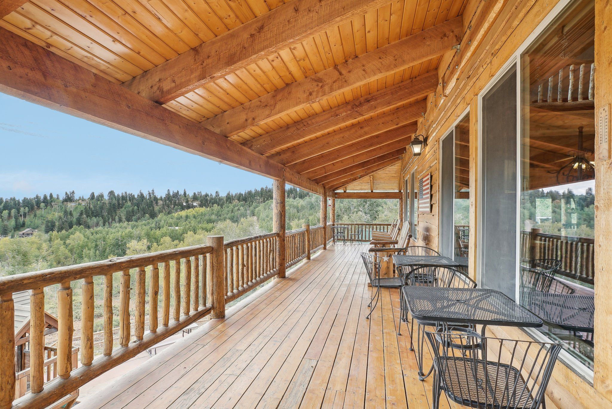 Long covered wraparound deck with tables and a mountain view